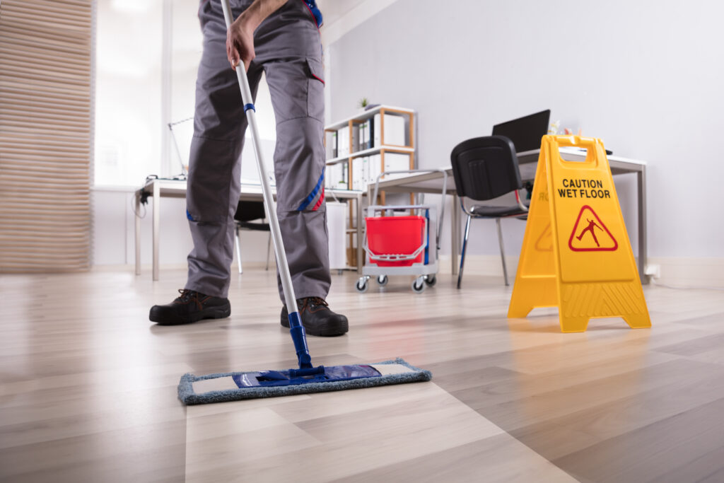 Low,Section,Of,Male,Janitor,Cleaning,Floor,With,Caution,Wet